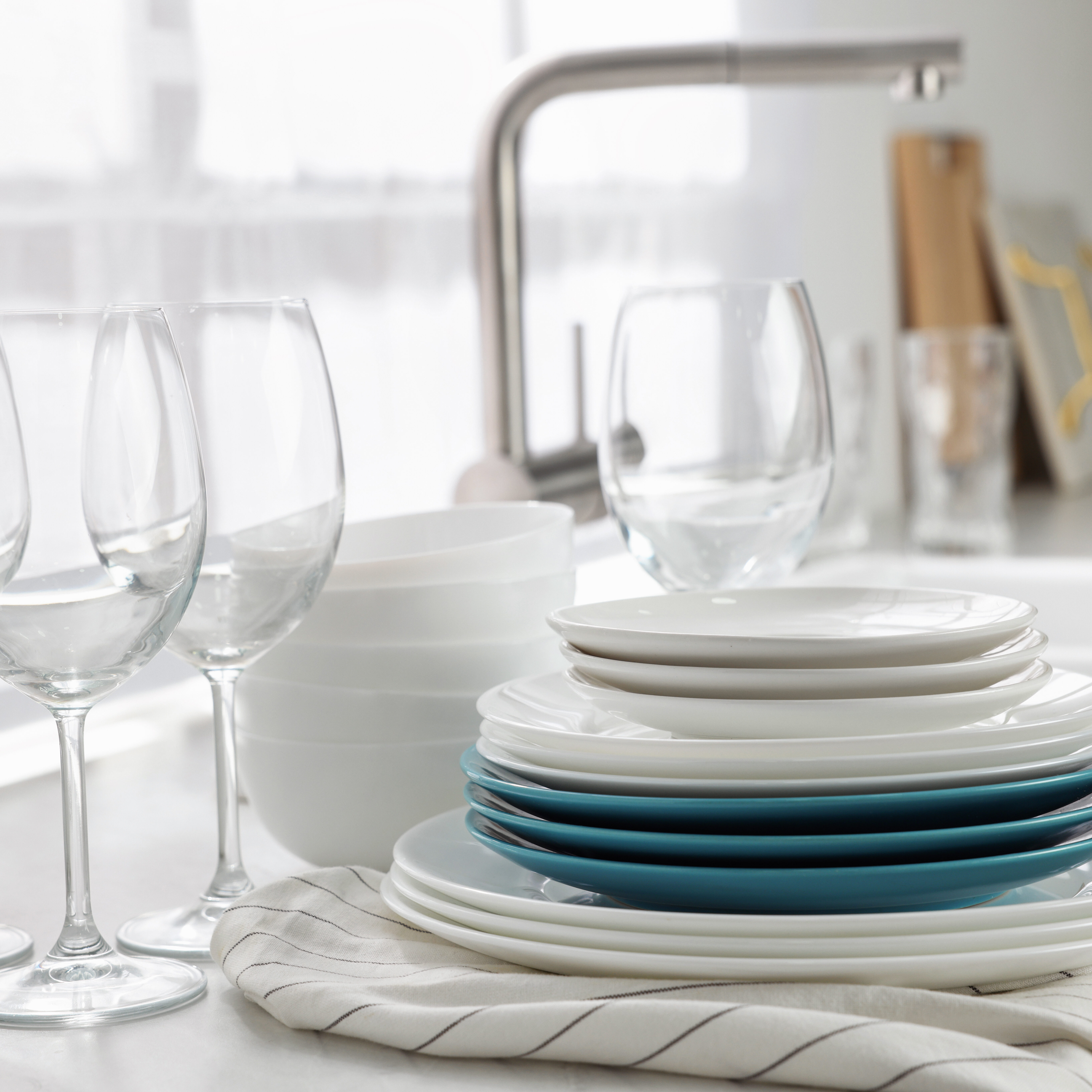 Different clean dishware and glasses on countertop near sink in kitchen